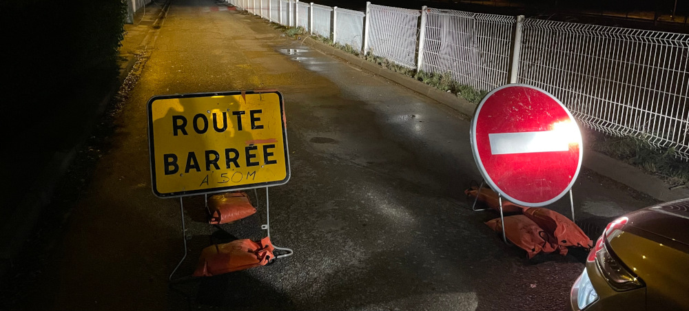 Des panneaux de chantier, bloquant une route, dans la nuit